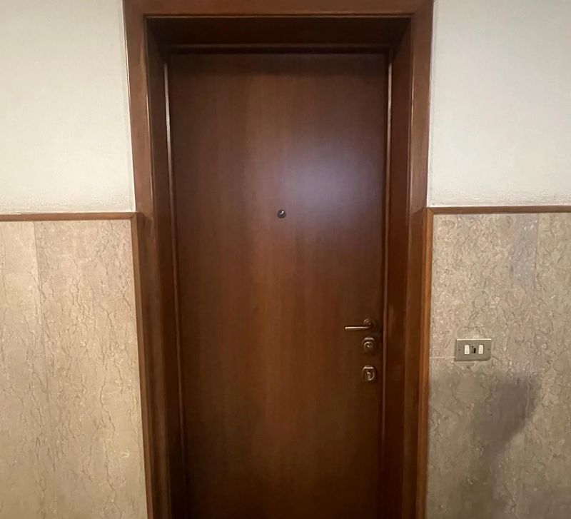 Porta blindata color noce sul pianerottolo di un condominio.